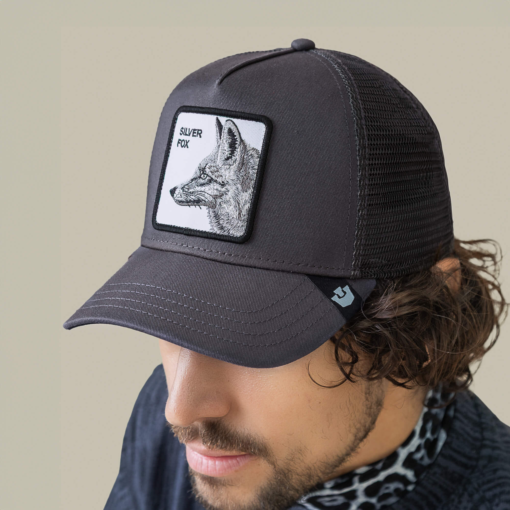 A man wearing a stylish Goorin Bros. Silver Foxxx cap—a black mesh baseball hat featuring a fox illustration patch on the front.