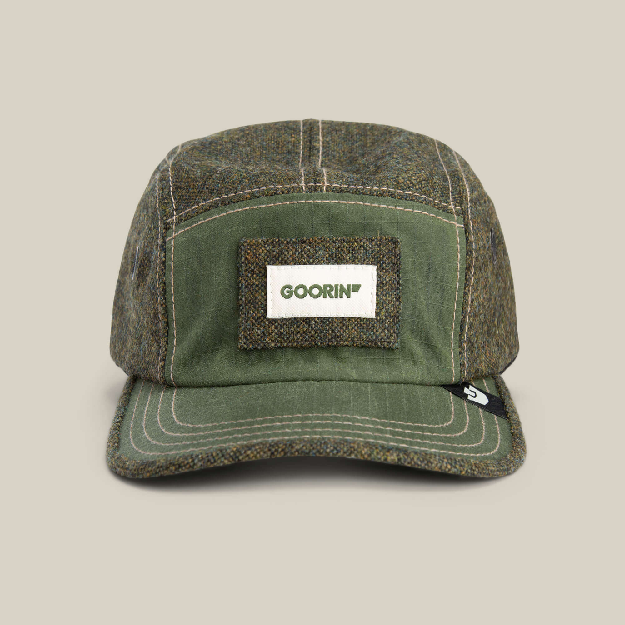 The Goorin Bros. Billed Demand hat in SHADE is a five-panel field cap featuring a rectangular front patch with green GOORIN text.