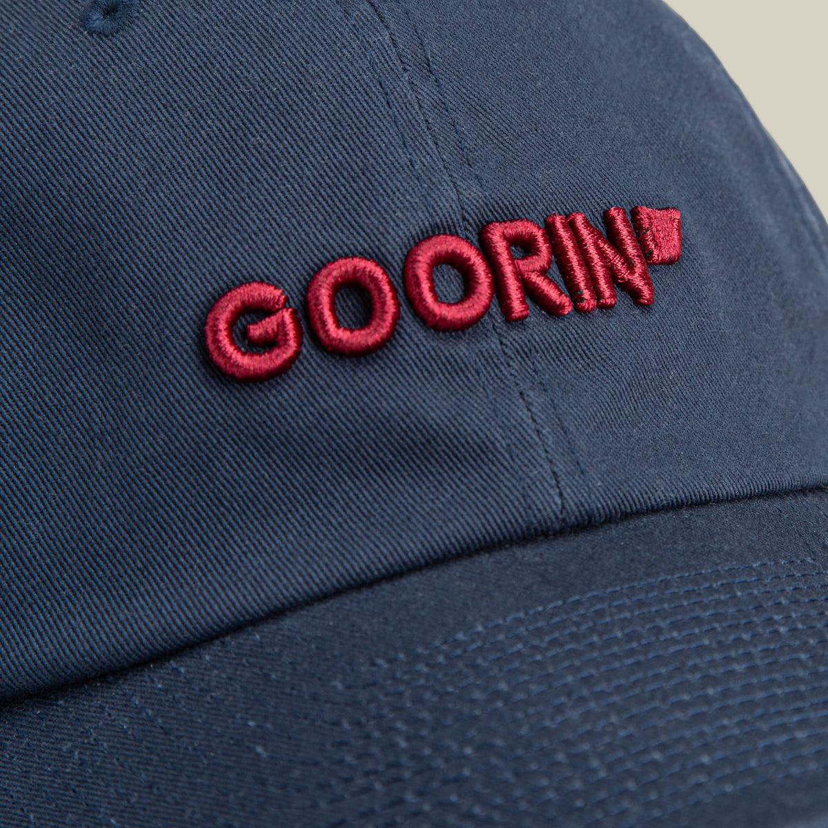 The Goorin Bros. Papa Core baseball cap in navy blue features red embroidered branding on the front, shown in a close-up studio product shot highlighting its cotton construction and minimalist design.