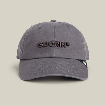 The Papa Core hat by Goorin Bros. features a gray curved brim and "GOORIN" embroidered in brown on the front, shown against a plain beige background.
