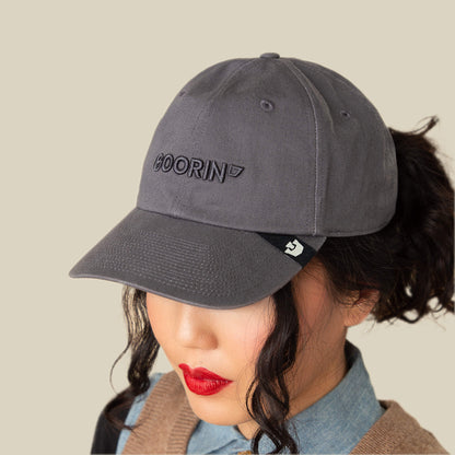 Wearing the Papa Core hat by Goorin Bros. with a soft crown and curved brim, a person with red lipstick and curled hair pairs it with a denim shirt and tan sweater, facing slightly downward.