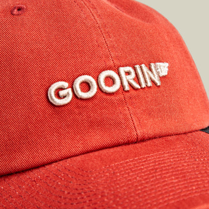 The Goorin Bros. Papa Core red baseball cap features white embroidered logo text on the front and a textured cotton construction, shown in a close-up studio product shot.