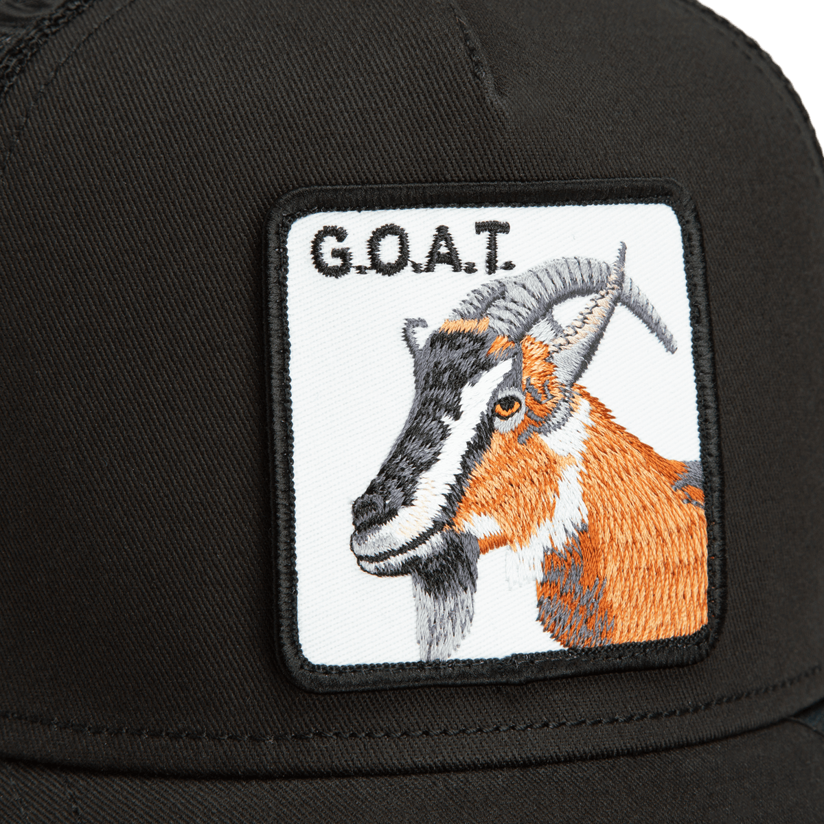 The Goorin Bros. Goat Trucker is a black trucker hat featuring an embroidered goat patch with orange and brown coloring and text reading G.O.A.T. on the front.