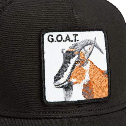The Goorin Bros. Goat Trucker is a black trucker hat featuring an embroidered goat patch with orange and brown coloring and text reading G.O.A.T. on the front.