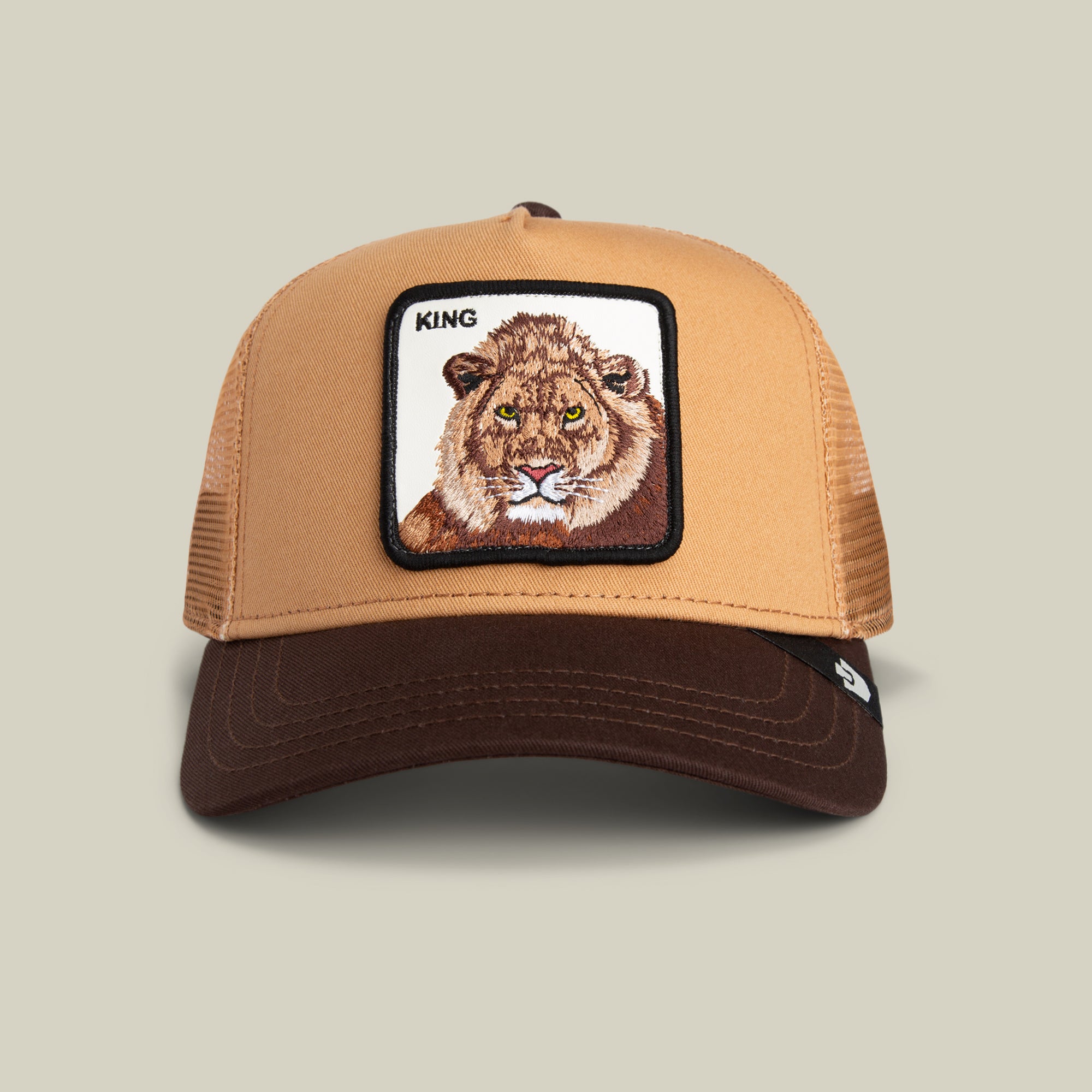 The King Trucker by Goorin Bros. is a tan and brown hat featuring an embroidered lion face and the word “KING” on the front—ideal for adding bold, stylish edge to your look.