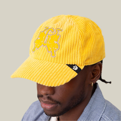 A person wearing a Goorin Bros. Bleacher Report cap with a corduroy crown and embroidered design, paired with a blue and white striped shirt, stands against a plain background.