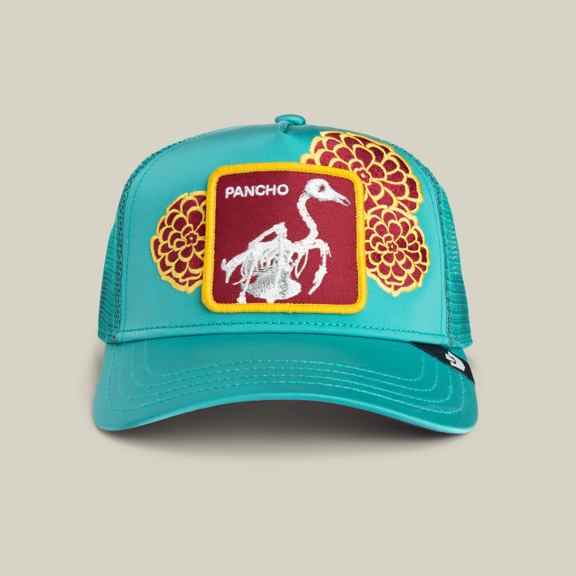 The Goorin Bros. Dia De Pancho trucker hat in LUMINOUS features a front patch with a white bird skeleton, stitched bone details, “PANCHO,” and vivid yellow flowers on red—perfect for channeling a rebel spirit.