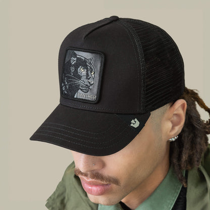 A person wearing The Panther by Goorin Bros.—a black mesh baseball cap featuring a panther patch—paired with a green jacket and green collared shirt.