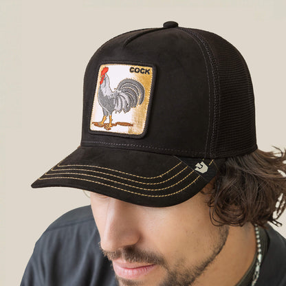 A man wears a Goorin Bros. Golden Cock black mesh trucker hat featuring gold stitching and a rooster patch labeled "Golden Cock.