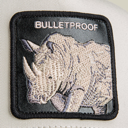 A close-up shows a patch on fabric featuring an embroidered rhinoceros with armor and "BULLETPROOF" above it, from the Bulletproof Trucker cap by Goorin Bros.
