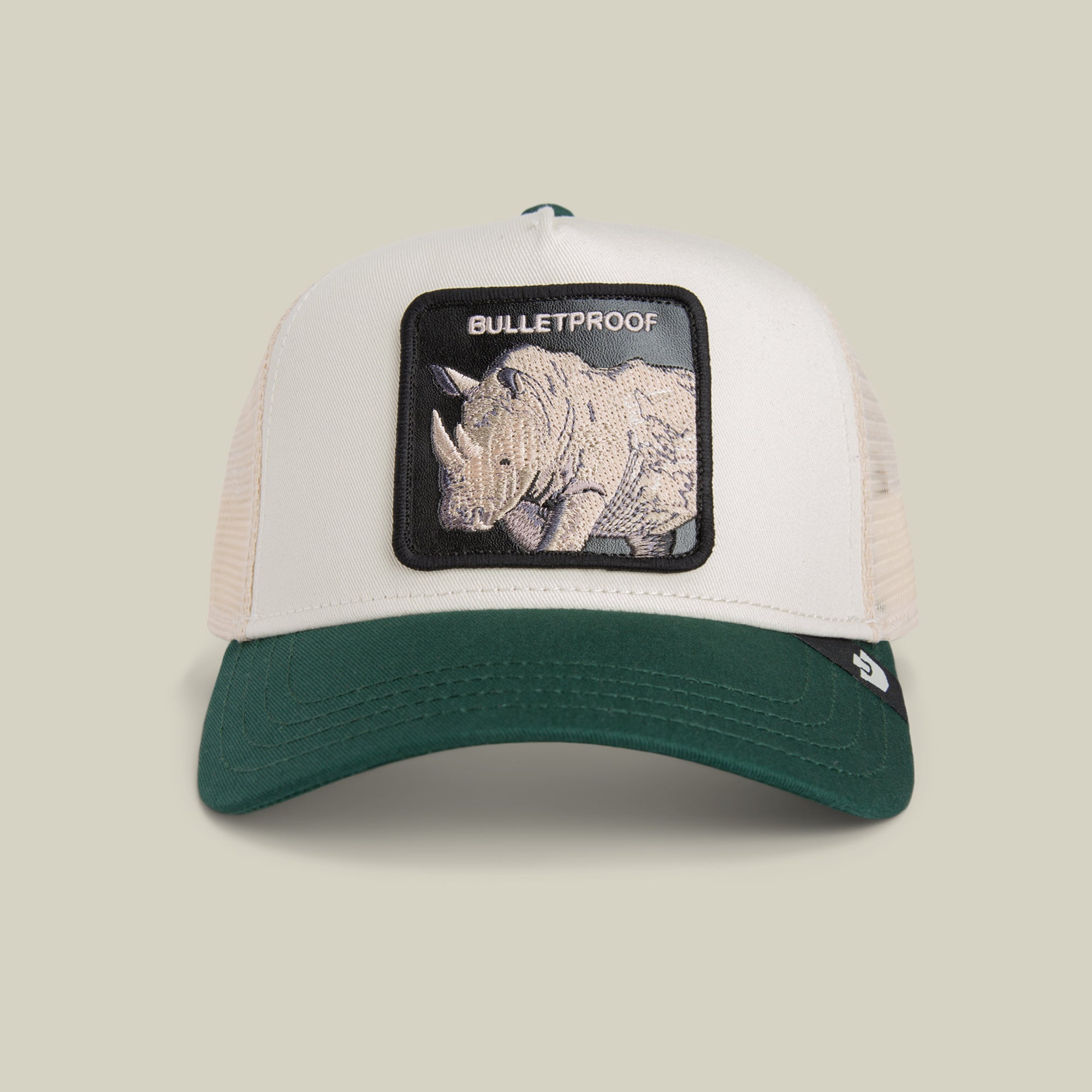 The Bulletproof Trucker by Goorin Bros. is a stylish hat with a green brim, beige mesh, and a front patch of a rhinoceros with "BULLETPROOF," embodying true Rhino armor style.