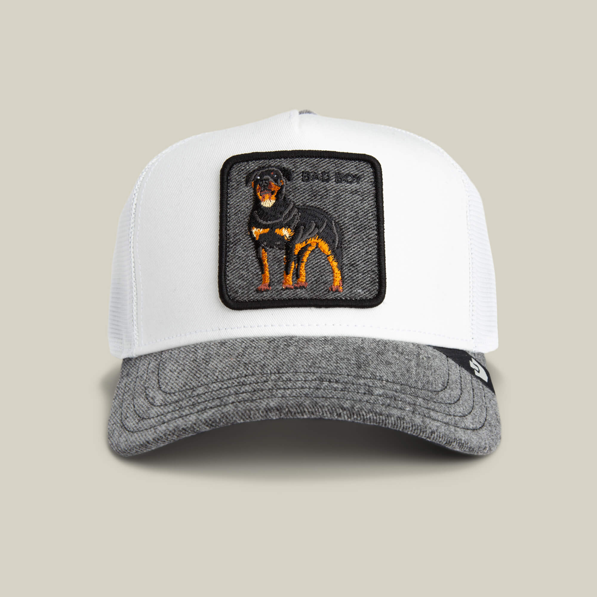 The Goorin Bros. Denim Bad Boy is a white and gray trucker cap with a patch showing an embroidered black and tan Rottweiler, perfect for fans of clean whites and classic style.