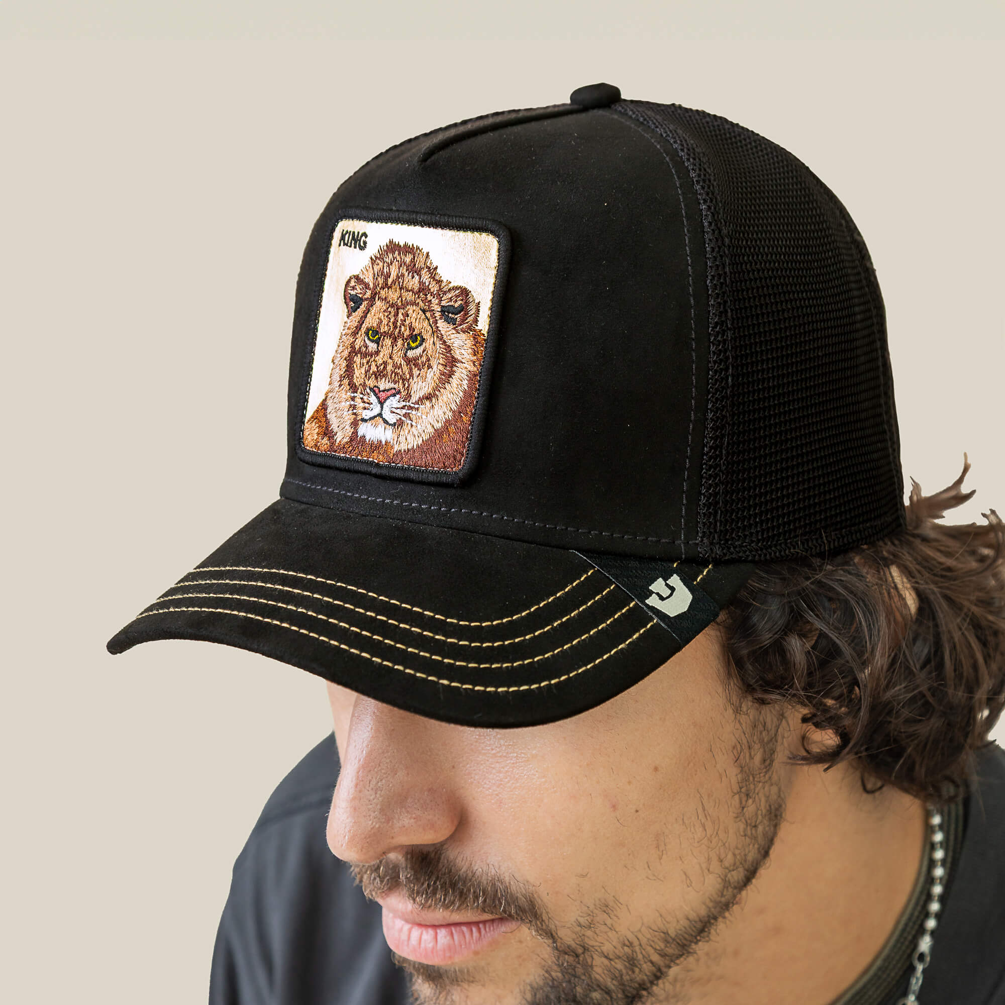 A man wears the Goorin Bros. Golden King black mesh baseball cap, featuring yellow stitching and a KING lion patch, celebrating the golden crown of the jungle.