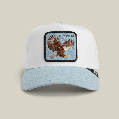 The Goorin Bros. Denim Fly High cap features a white design with a light blue brim, a bold eagle patch in flight, and "FLY HIGH" text—ideal for altitude lovers craving standout elevation style.