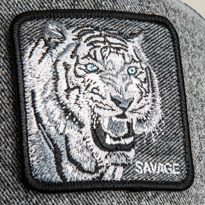 A close-up of the Goorin Bros. Denim Savage patch: an embroidered white tiger with blue eyes and "SAVAGE" stitched in white—perfect for bold streetwear caps.