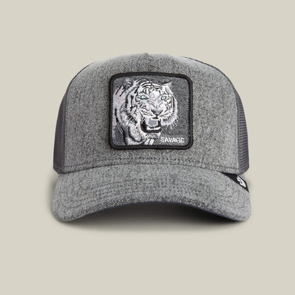 The Goorin Bros. Denim Savage hat is a gray trucker cap with mesh back and a front patch showing bold tiger embroidery and "SAVAGE" in white—an eye-catching streetwear accessory.
