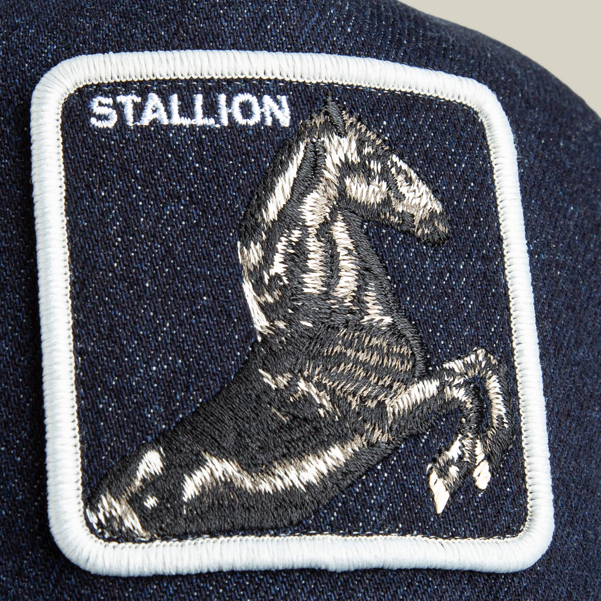 The Goorin Bros. Denim Stallion patch features a black and white embroidered horse with “STALLION” in white on a dark blue fabric—perfect for adding arena style to your favorite cap.