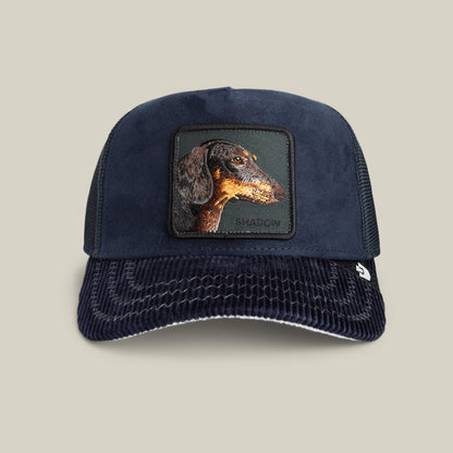 The Shadow Remix by Goorin Bros. is a navy blue mesh hat with a midnight corduroy brim, dachshund patch, and SHADOW embroidery—a perfect luxury introvert accessory.