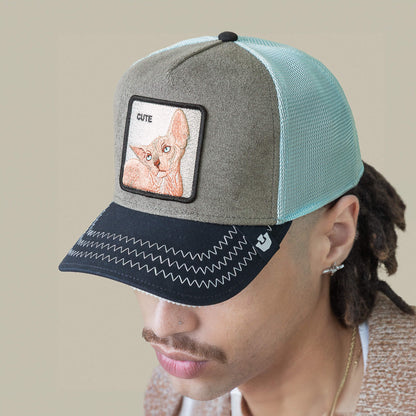 Person wearing the Goorin Bros. Cute Remix hat, featuring green and black mesh with a "CUTE" patch and hairless cat design; neutral background.
