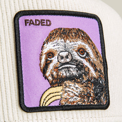 The Goorin Bros. Faded Remix is a cream corduroy hat with a ribbed texture, featuring a rectangular embroidered patch of a sloth and the word "FADED" on a purple background.