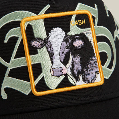 The Goorin Bros. Old English Cash hat is black with an ornate cow patch, a yellow square border, and bold yellow “CASH” lettering in Old English script.