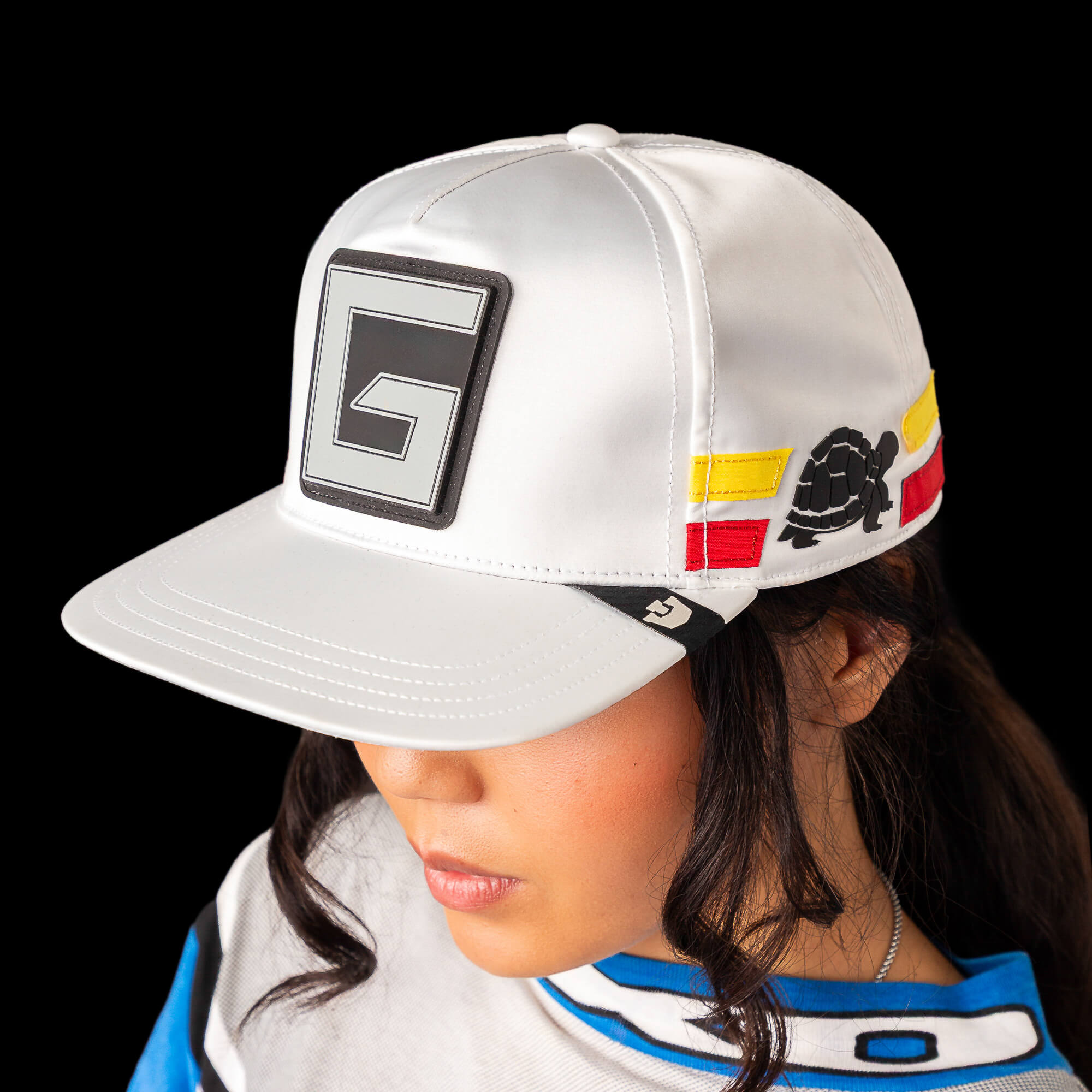 Person wearing the Pole Position - Speedbump hat by Goorin Bros., featuring a large G logo on the front, colorful side patches, and a subtle gloss finish, set against a black background.