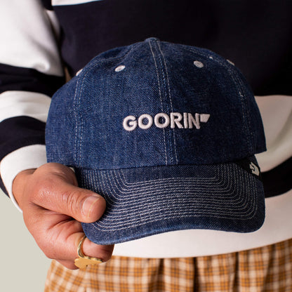 A person holds the Papa Core Denim low profile blue denim hat by Goorin Bros., featuring the GOORIN wordmark embroidered in white on the front.