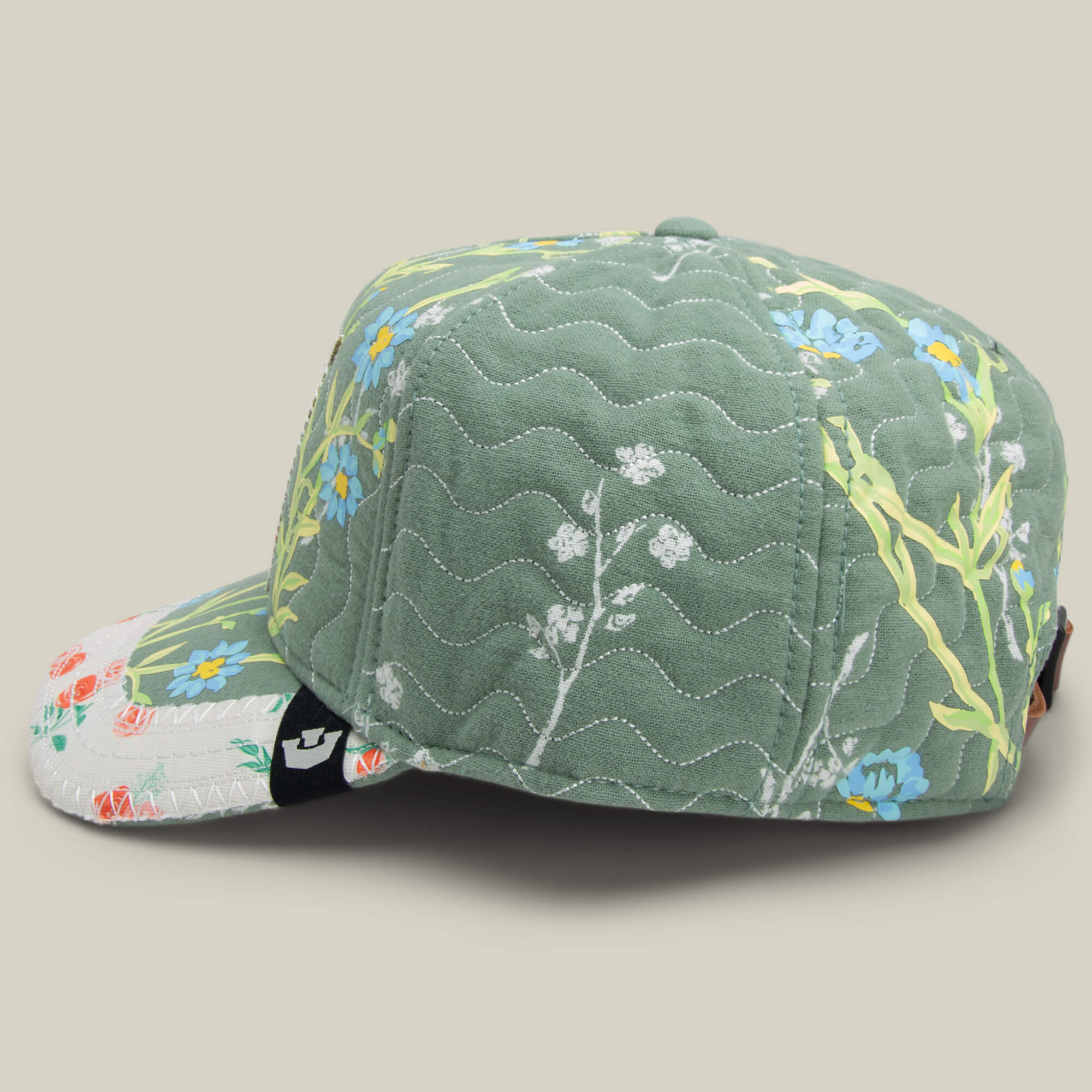 The Goorin Bros. Vol. 1 - Quiltbag: Laugh cap is a green quilted OG Trucker hat with blue and white floral patterns and light green stems, displayed on a neutral background.
