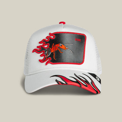 The Goorin Bros. Fire Flames hat is a white mesh trucker cap with bold red and black flame graphics on the brim and a patch featuring a red ant, fire flames, and the word "FIRE.