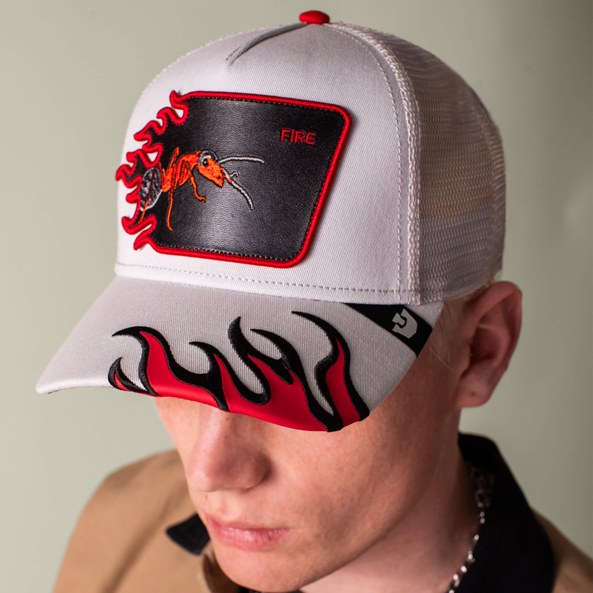 A person wears the Goorin Bros. Fire Flames trucker hat with a red ant patch labeled "FIRE" and bold red and black fire flames on the brim.