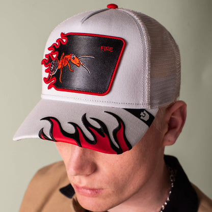 A person wears the Goorin Bros. Fire Flames trucker hat with a red ant patch labeled "FIRE" and bold red and black fire flames on the brim.