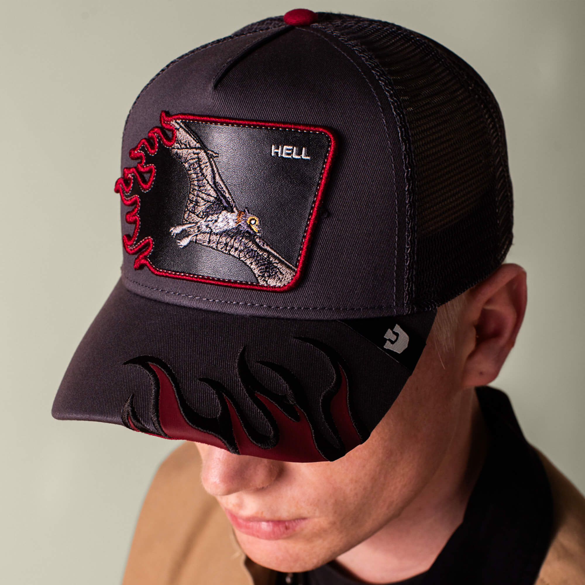 Someone is wearing the Goorin Bros. "Hell Flames" charcoal trucker hat, which features flames on the brim and a patch with a dragon and the word HELL on the front.