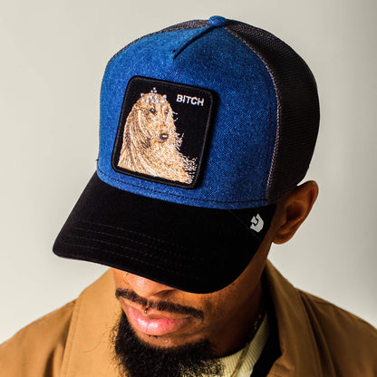 A man wearing the Hound Dawg hat by Goorin Bros.—a blue and black denim cap with a hound dog patch.