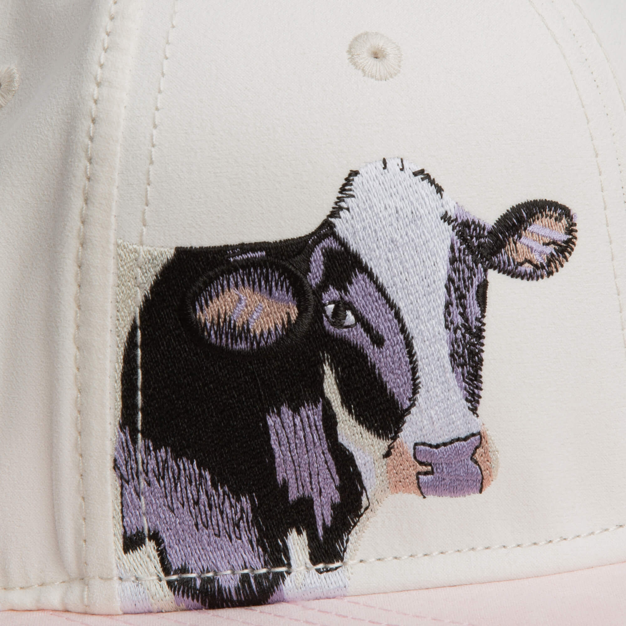 Close-up of the Goorin Bros. 6-Panel Cash Script hat in cream, featuring an embroidered black and white cow’s face on the front panel.