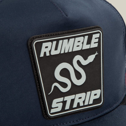 Close-up of the Pole Position - Rumble Strip navy cap by Goorin Bros., featuring a snake patch with a white graphic and "RUMBLE STRIP" in bold—a perfect accessory for drift drivers who grip tight around every corner.