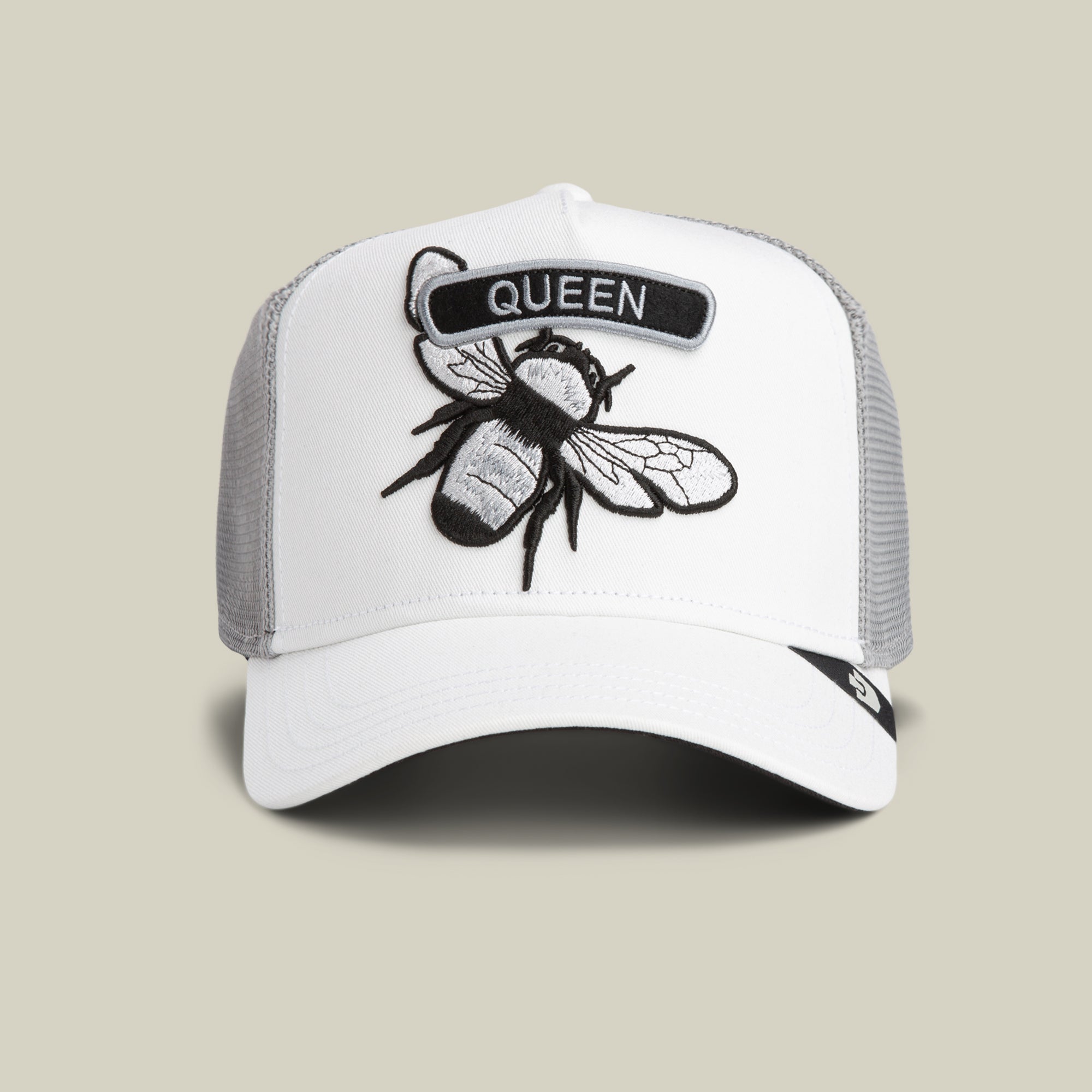The Classic Rocker - Queen by Goorin Bros. is a DUST-colored mesh trucker hat with an embroidered bee and black QUEEN patch, perfect for fans of the iconic rocker vibe.