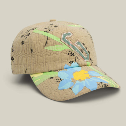 The Vol. 1 - Quiltbag: G Papa cap by Goorin Bros. features a beige quilted design, black floral prints, a bold blue and yellow flower graphic with green accents, and a raised G logo on the front.