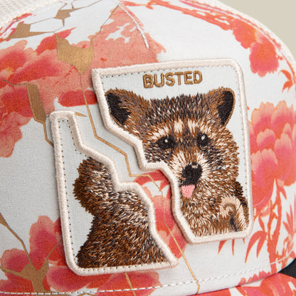 Close-up of the Break The Law hat by Goorin Bros., with a floral pattern and an embroidered bear patch bordered in jagged edges, reading BUSTED—a must-have for one piece-inspired streetwear fans.