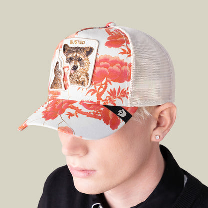 A person wears the Goorin Bros. "Break The Law" mesh trucker hat, featuring a red floral print inspired by One Piece and a front patch with a bear and the word BUSTED.