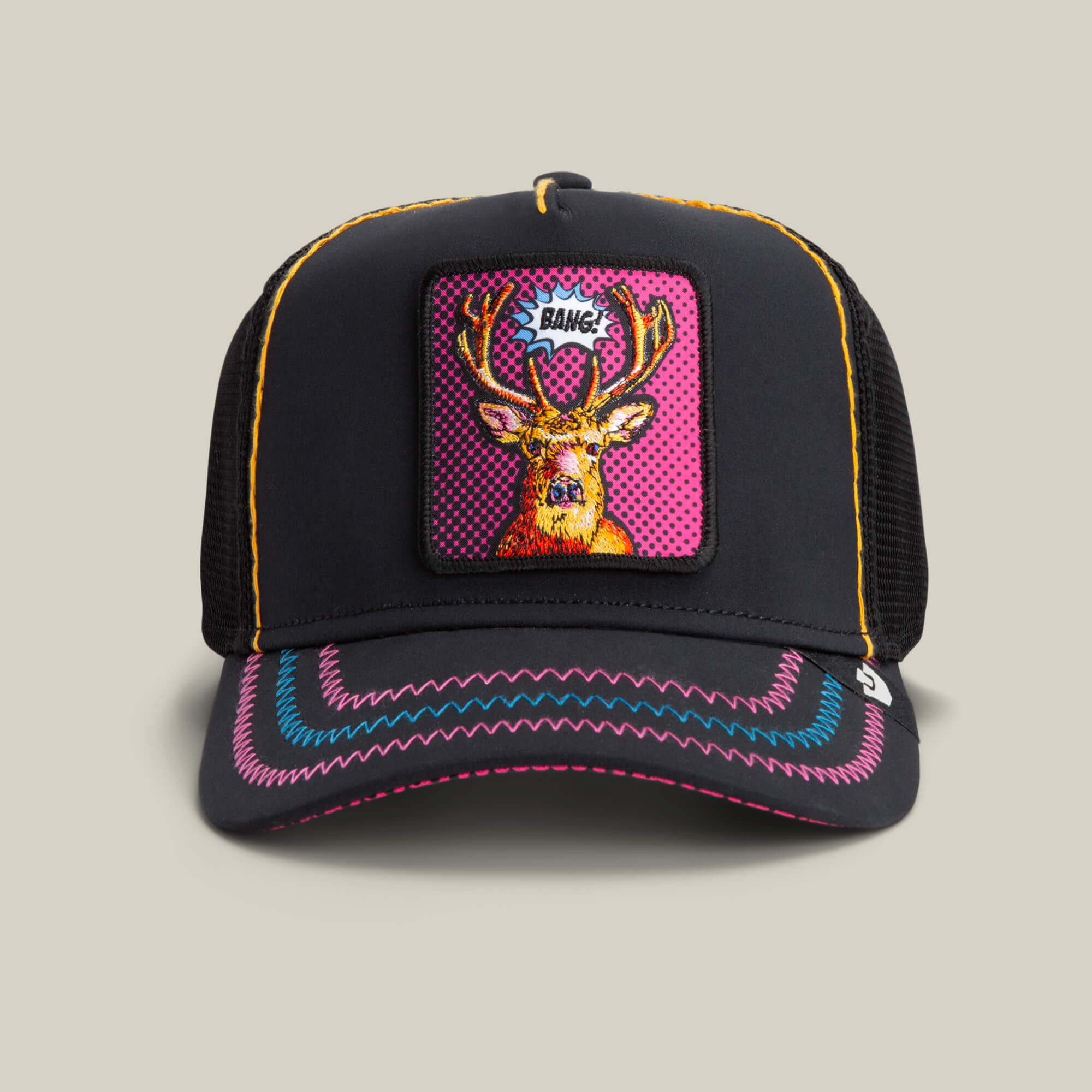 The Earned Media by Goorin Bros. is a VOID black trucker hat with neon stitching, a Pop Art deer patch with multicolored antlers, and "BANG!" above its head.