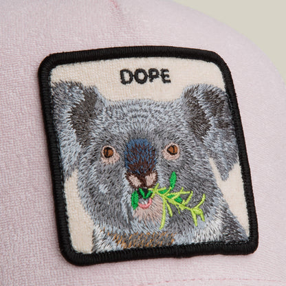 A cozy pale pink hat by Goorin Bros., the Terry Cloth Koala, features a soft square patch showing a koala eating leaves with "DOPE" above it.