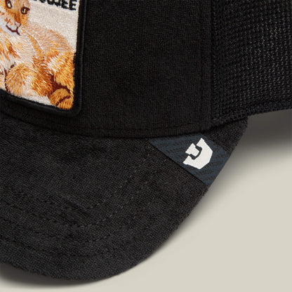 Close-up of the Goorin Bros. "Terry Cloth Cat" cap, crafted from plush black terry cloth with an embroidered orange and white cat patch and a subtle white logo on the brim, offering luxury loungewear softness.