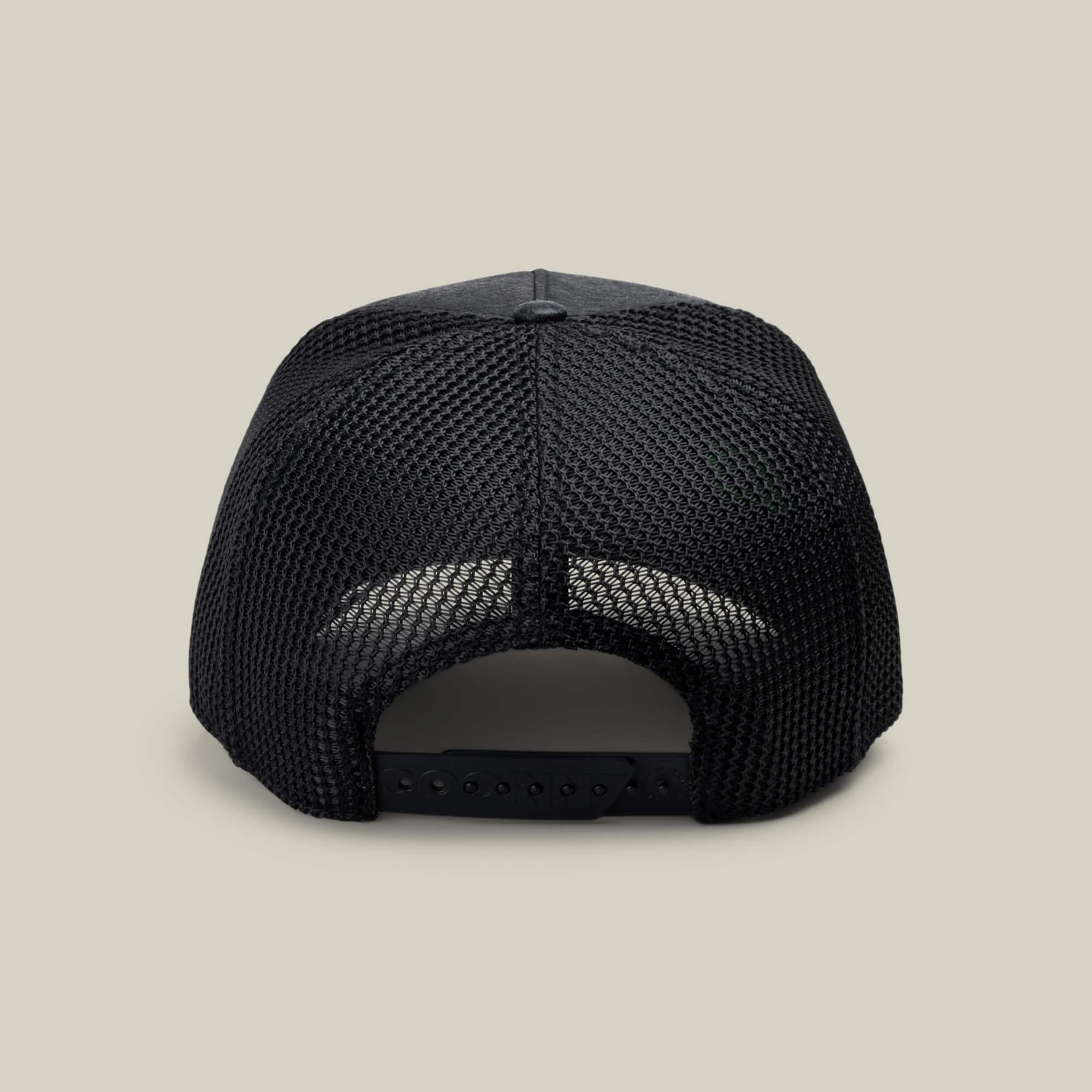 The NeoBrand STALLION trucker hat by Goorin Bros. is shown from the rear, displaying its black mesh back, matching snapback closure, and monochrome embroidery on a simple light beige background.