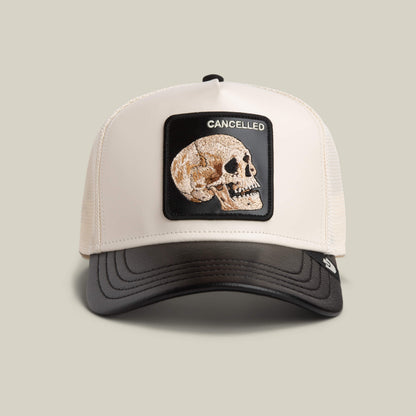 The Goorin Bros. Faux Leather Skull trucker hat features a VOID/CHALK colorway with a skull patch and "CANCELLED" embroidery, offering neutral, versatile style.