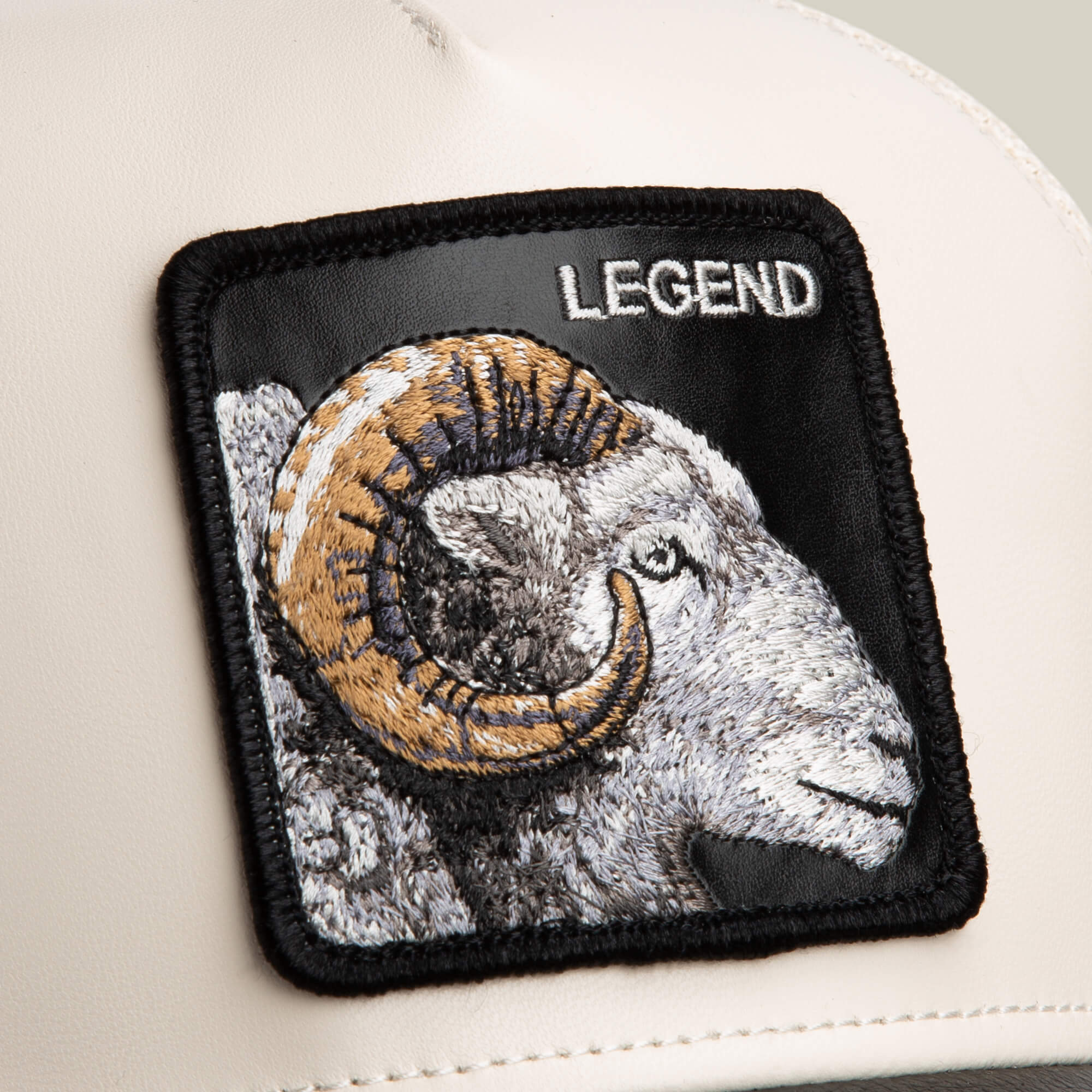 Close-up of the Goorin Bros. Faux Leather Ram, showing cream faux leather fabric with a ram patch featuring an embroidered ram’s head, curved horns, and "LEGEND" stitched in white.