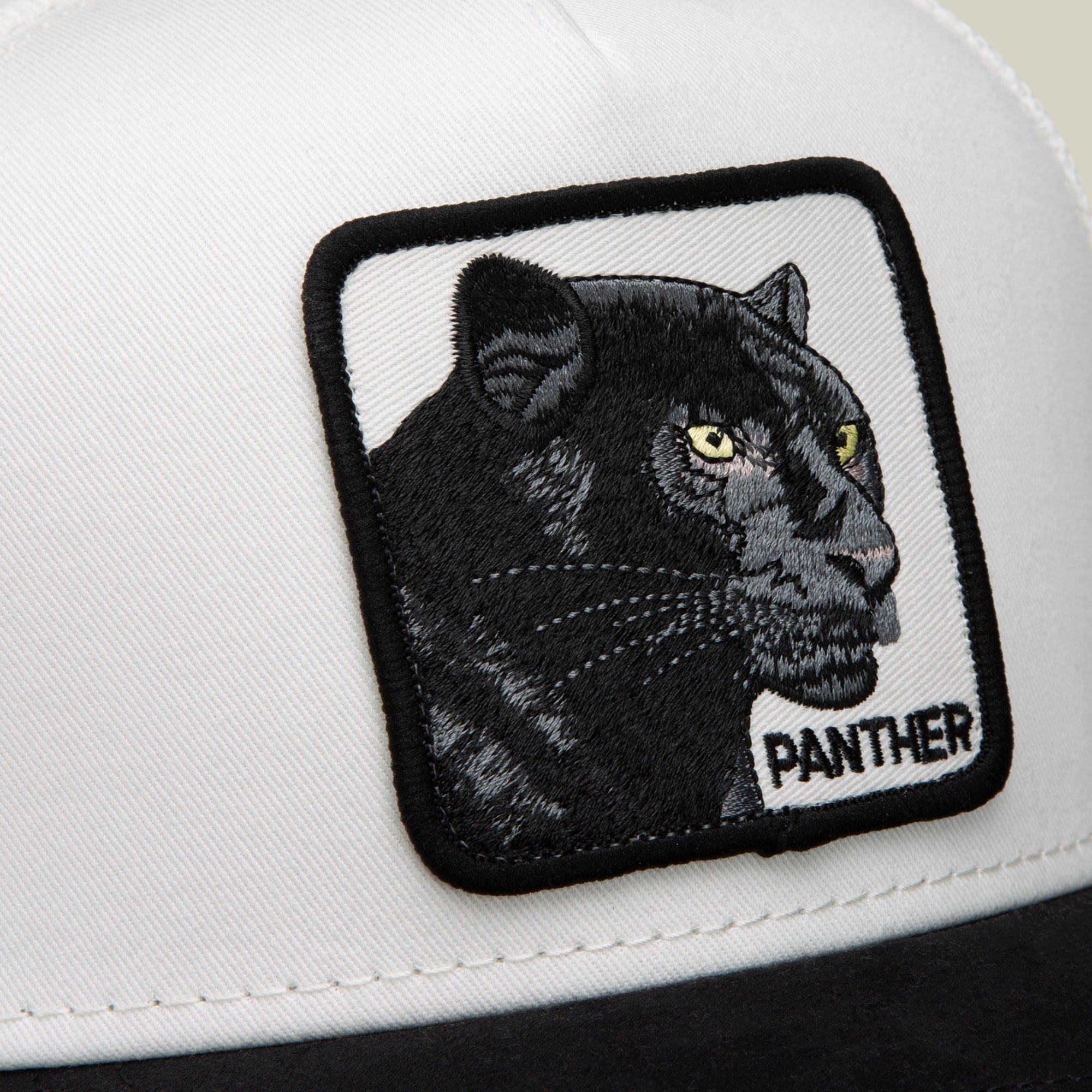 A close-up of the Goorin Bros. Suede Black Panther cap in a black and white colorway, showcasing a bold patch with an embroidered black panther head and “PANTHER” text.