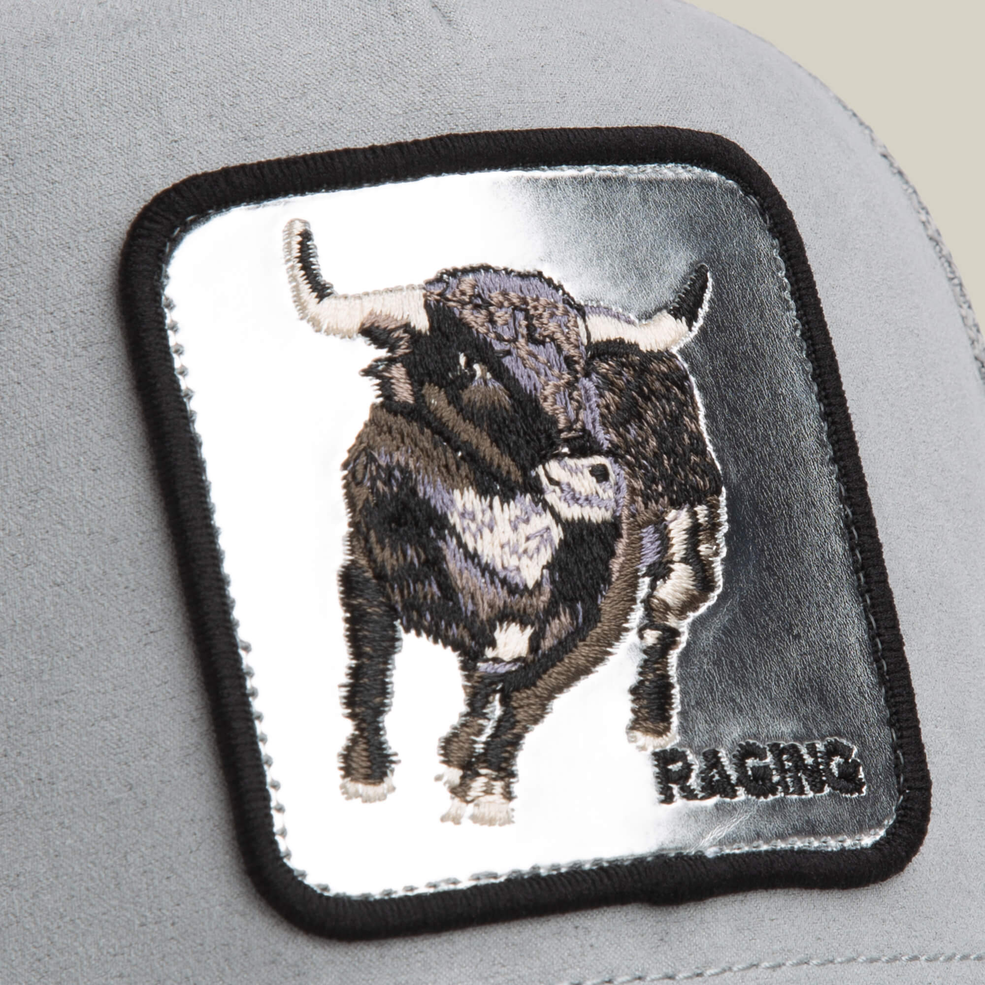 A close-up of the Goorin Bros. Silver Bull patch, featuring an embroidered silver bull and "RACING" in black caps—ideal for adding flair to your favorite gray trucker hat.