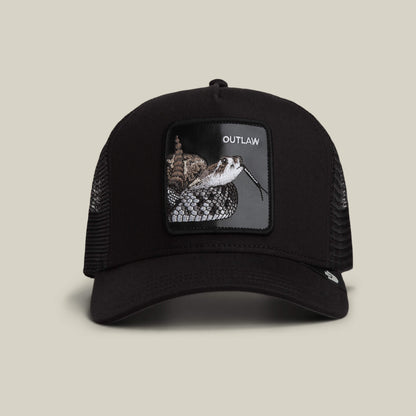 The Goorin Bros. Outlaw Trucker in VOID color is a black hat with a mesh back, showcasing a striking rattlesnake patch and bold white "OUTLAW" text on the front.