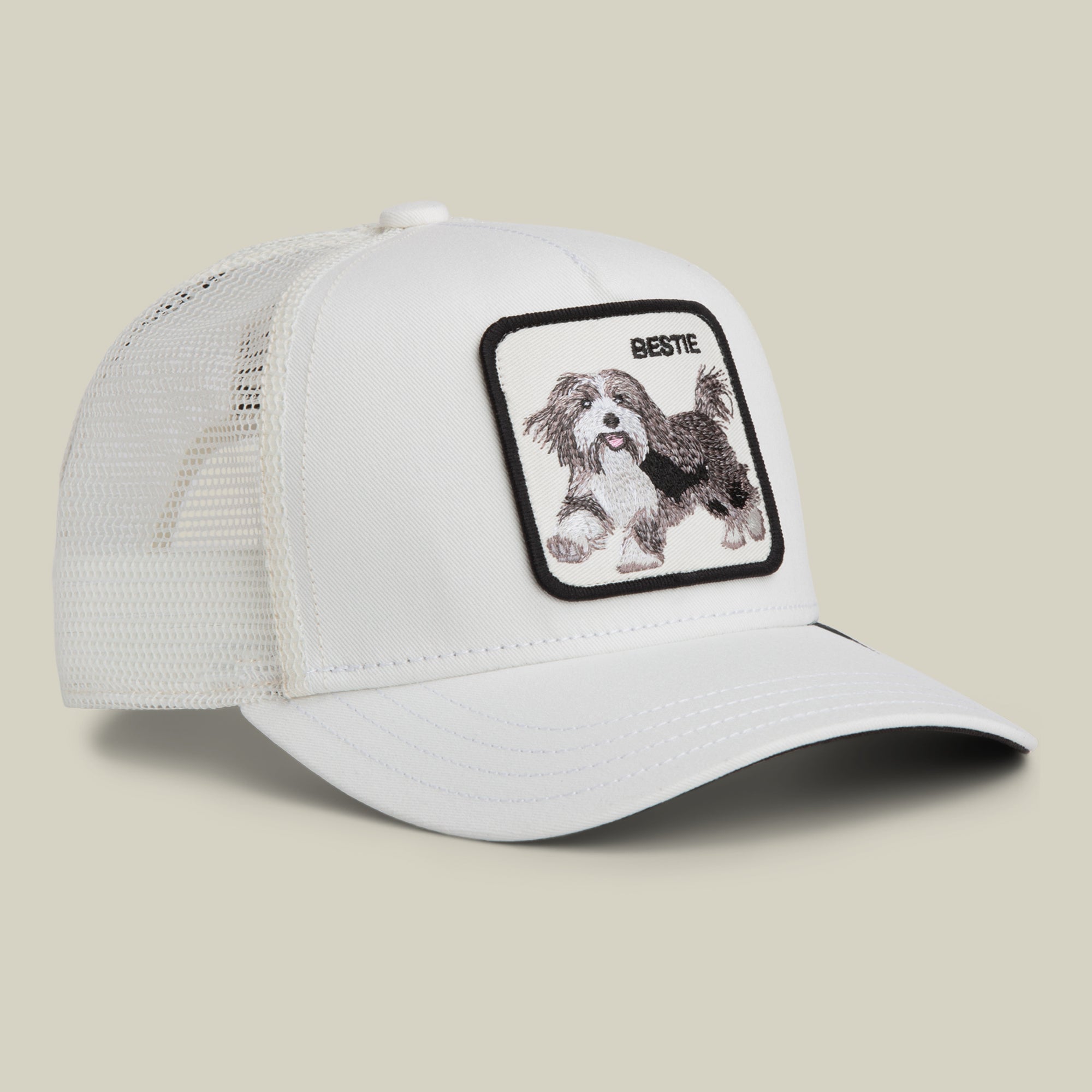 The Goorin Bros. Bestie Trucker is a white mesh trucker cap with a patch featuring an embroidered running dog and the word “BESTIE” above it.