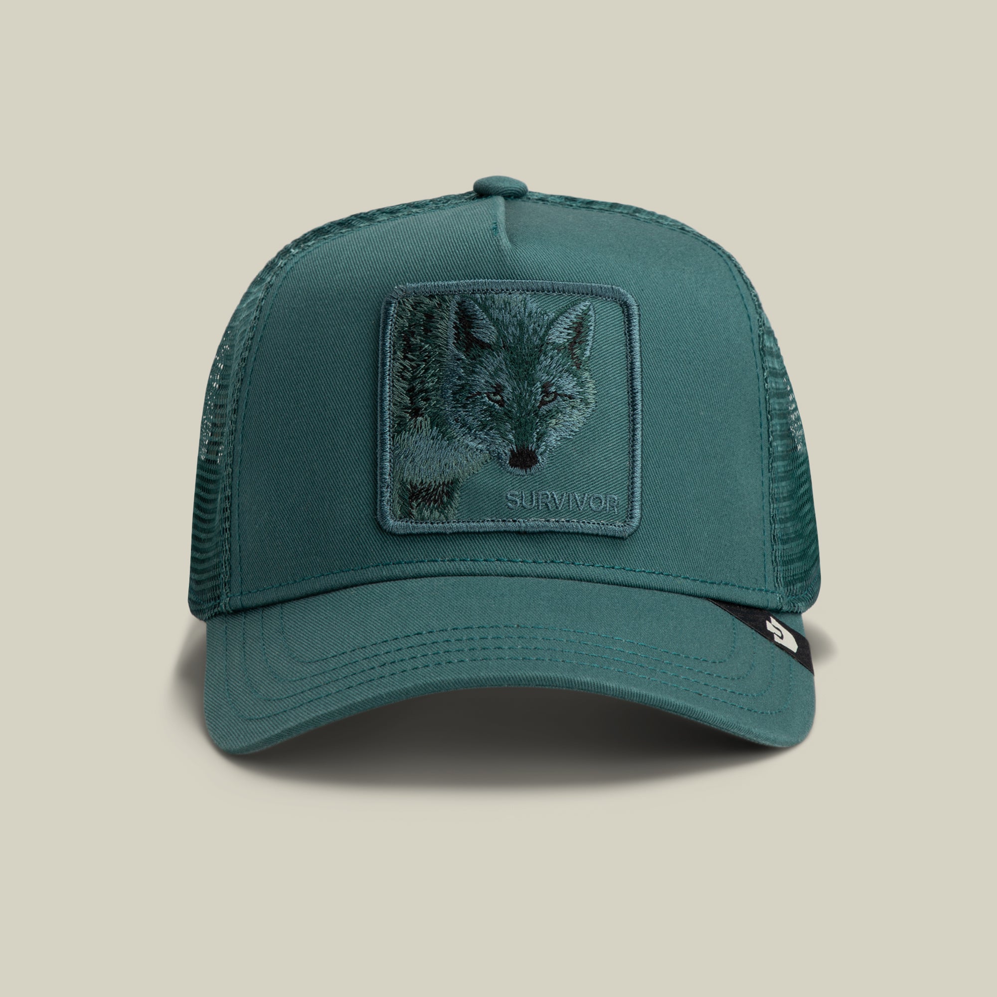 The Mirage Survivor by Goorin Bros. is a SEA-colored trucker hat featuring an embroidered wolf and the word SURVIVOR on the front, making it the ideal cap for outdoor adventures.